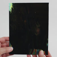 Video of the Black Iridescent glass plate in black, opaque and iridescent finish, 15x19cm, held up and tilted to show its pattern and transparency.