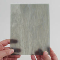 Video of the shadow wispy glass plate in grey translucent swirls, 15x19cm, held up and tilted to show its pattern and transparency