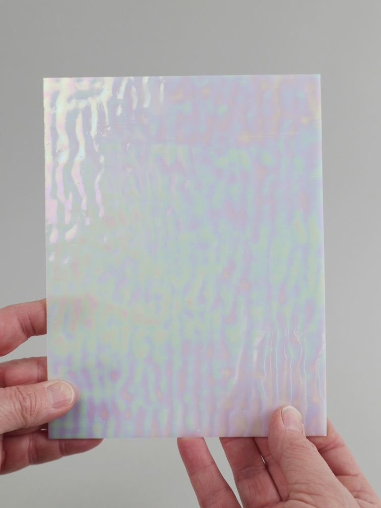 Video of the coconut pearl glass plate in white translucent iridescent, 15x19cm, held up and tilted to show its pattern and transparency
