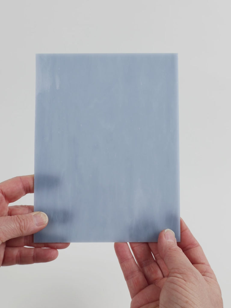 Video of the soft cadet grey glass plate in grey translucent marbled, 15x19cm, held up and tilted to show its pattern and transparency