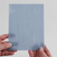 Video of the soft cadet grey glass plate in grey translucent marbled, 15x19cm, held up and tilted to show its pattern and transparency