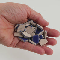 Video of Flip ceramic puzzle pieces in cobalt, opaque glazed porcelain, 4–20 mm, held in a hand and poured out to show their shapes and finish