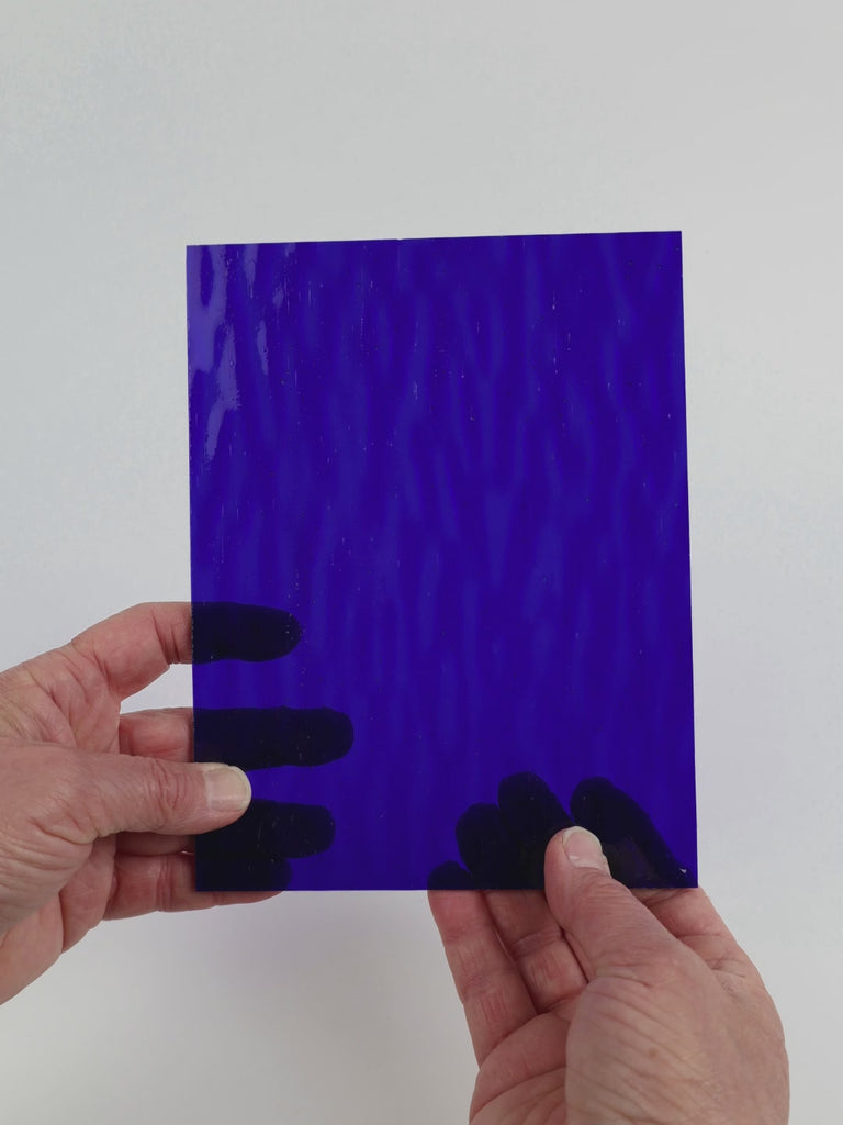 Video of the Deep Blue Ripple glass plate in ripple transparent blue, 15x19cm, held up and tilted to show its pattern and transparency