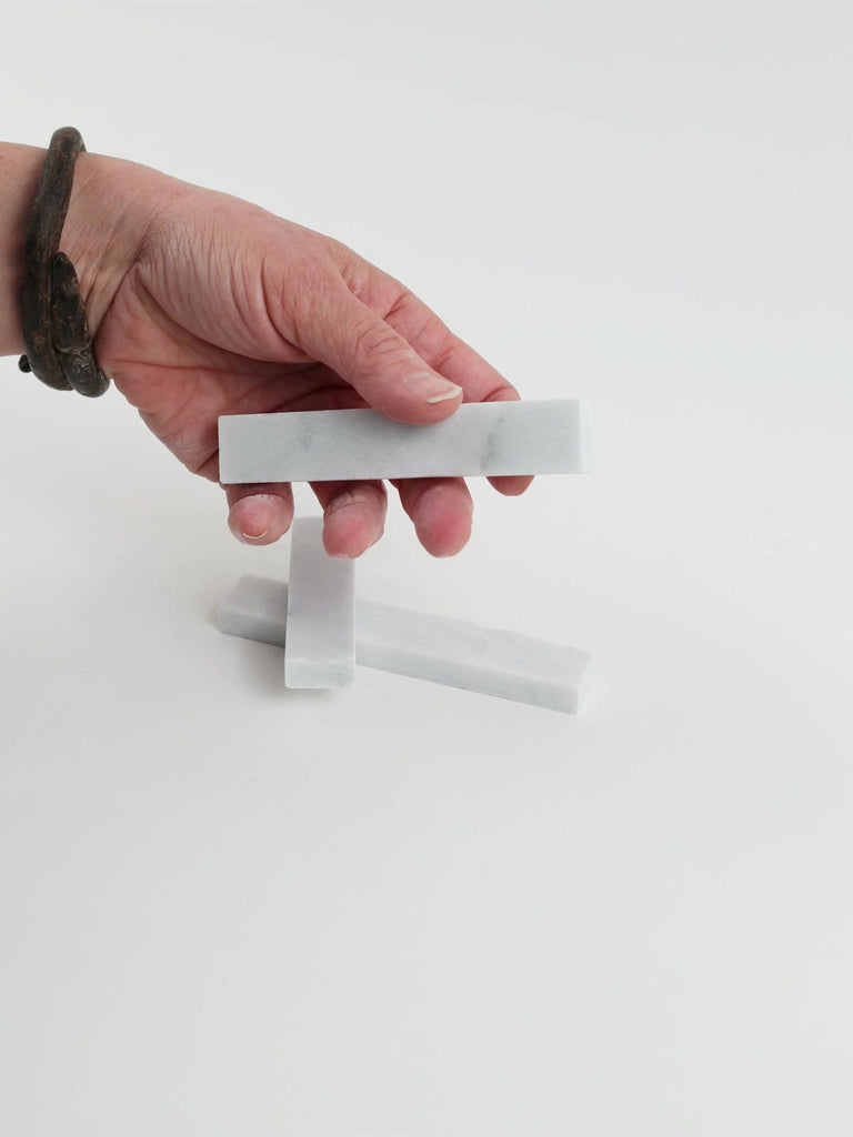 Video of Marble Bars XL Bianco Carrara in opaque white natural marble, 1–20 cm long and 8 mm thick, picked up by hand and turned to show their length, colour and natural veining