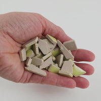 Video of Flip ceramic puzzle pieces in ochre yellow, opaque glazed porcelain, 4–20 mm, held in a hand and poured out to show their shapes and finish
