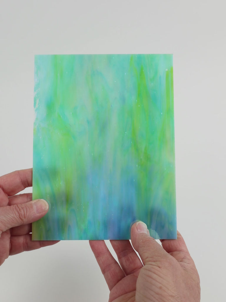 Video of the Teal Marbled Iridised glass plate in iridescent translucent teal, 15x19cm, held up and tilted to show its pattern and transparency