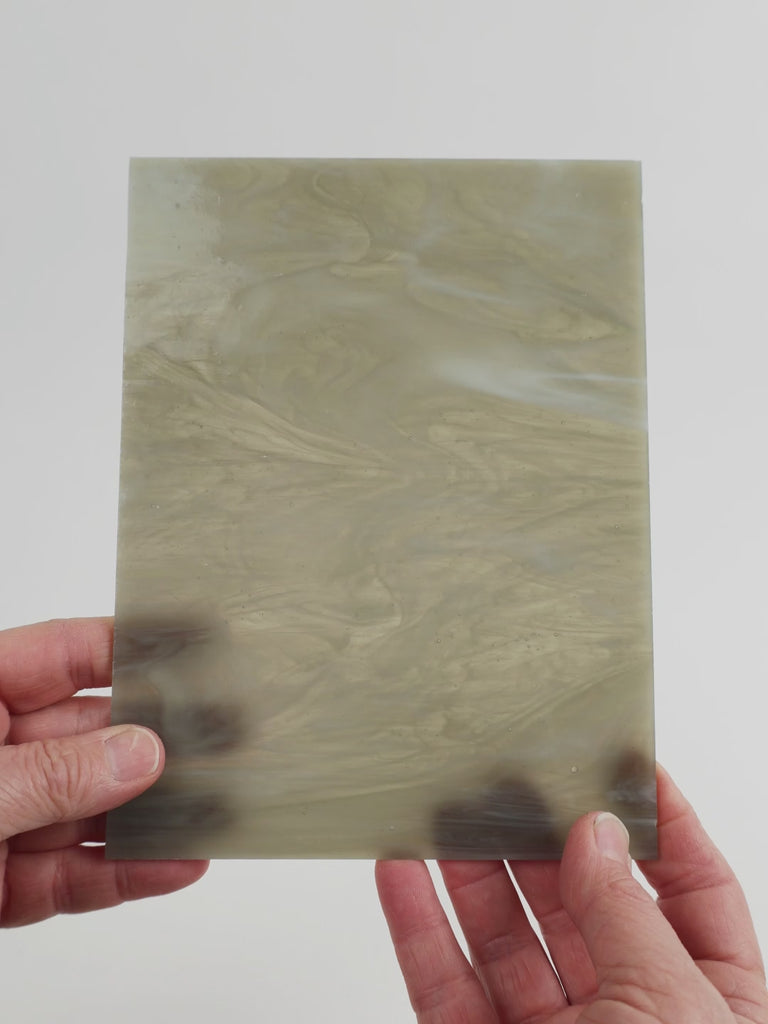 Video of the grey feather glass plate in grey translucent swirl, 15x19cm, held up and tilted to show its pattern and transparency
