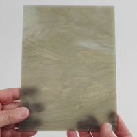Video of the grey feather glass plate in grey translucent swirl, 15x19cm, held up and tilted to show its pattern and transparency