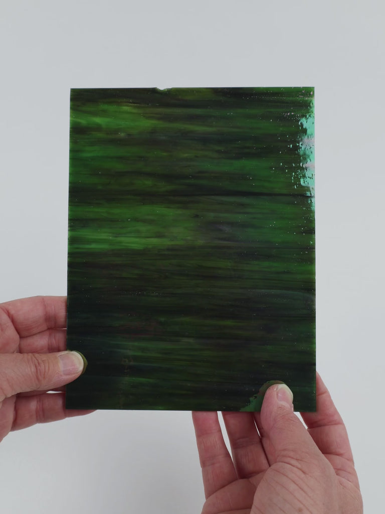 Video of the Dark Forest Iridised glass plate in iridised translucent green, 15x19cm, held up and tilted to show its pattern and transparency