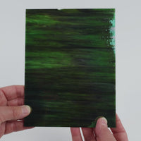 Video of the Dark Forest Iridised glass plate in iridised translucent green, 15x19cm, held up and tilted to show its pattern and transparency